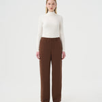 Chandail Turtleneck blanc ivoire pour femme et pantalon ample brun à taille élastique.