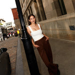 Pantalon brun large et camisole blanche pour femme.