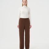 Chandail Turtleneck blanc ivoire pour femme et pantalon ample brun à taille élastique. 